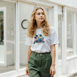 Woman wearing a white Retro Paradise T-shirt for women with palm-tree graphic, casual summer style.