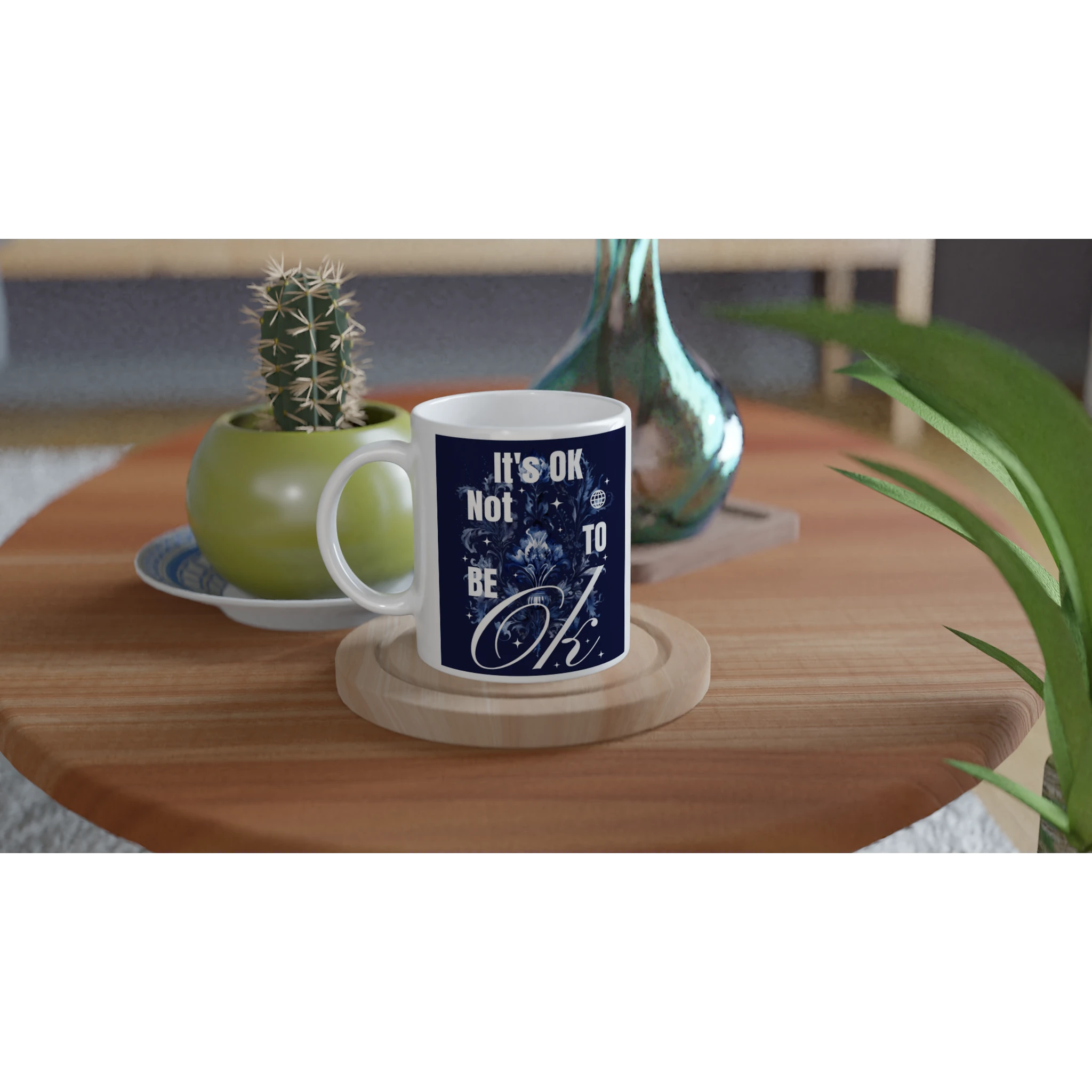 White ceramic mug with navy 'It's OK Not To Be OK' slogan on a wooden coaster, a thoughtful mental health gift.