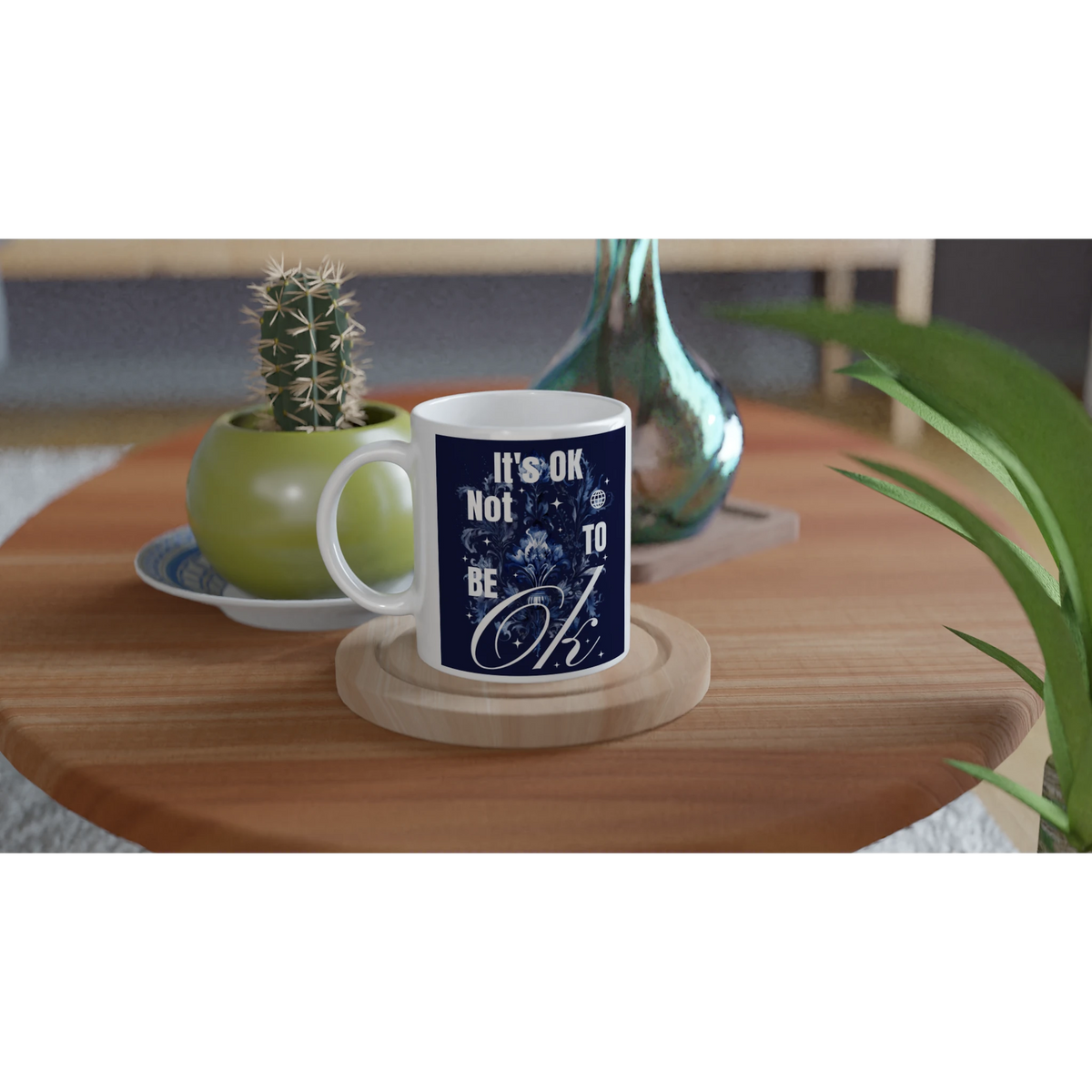 White ceramic mug with navy 'It's OK Not To Be OK' slogan on a wooden coaster, a thoughtful mental health gift.
