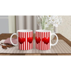 Two red-striped heart mugs on a table with white flowers in the background.