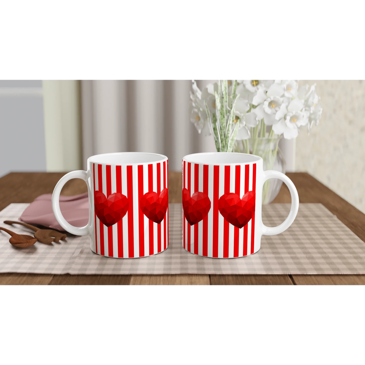 Two red-striped heart mugs on a table with white flowers in the background.