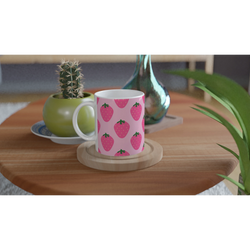 Cute pink strawberry mug with kawaii fruit pattern on a wooden table near a cactus.