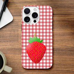 Red gingham iPhone case featuring a cute cartoon strawberry on a wooden desk background.