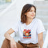 Woman wearing a white Island Breeze Hawaii T Shirt with Aloha graphic, palm trees and sunset over Paradise Island.