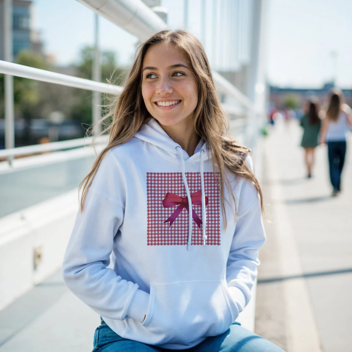 Young woman wearing a light-blue hoodie with a red gingham chest panel and bow, casual coquette style.