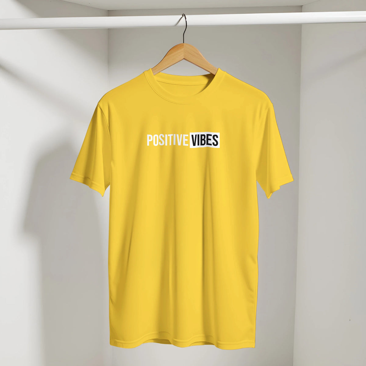 Yellow Positive Vibes T-shirt on a wooden hanger in a closet, retro slogan streetwear look.
