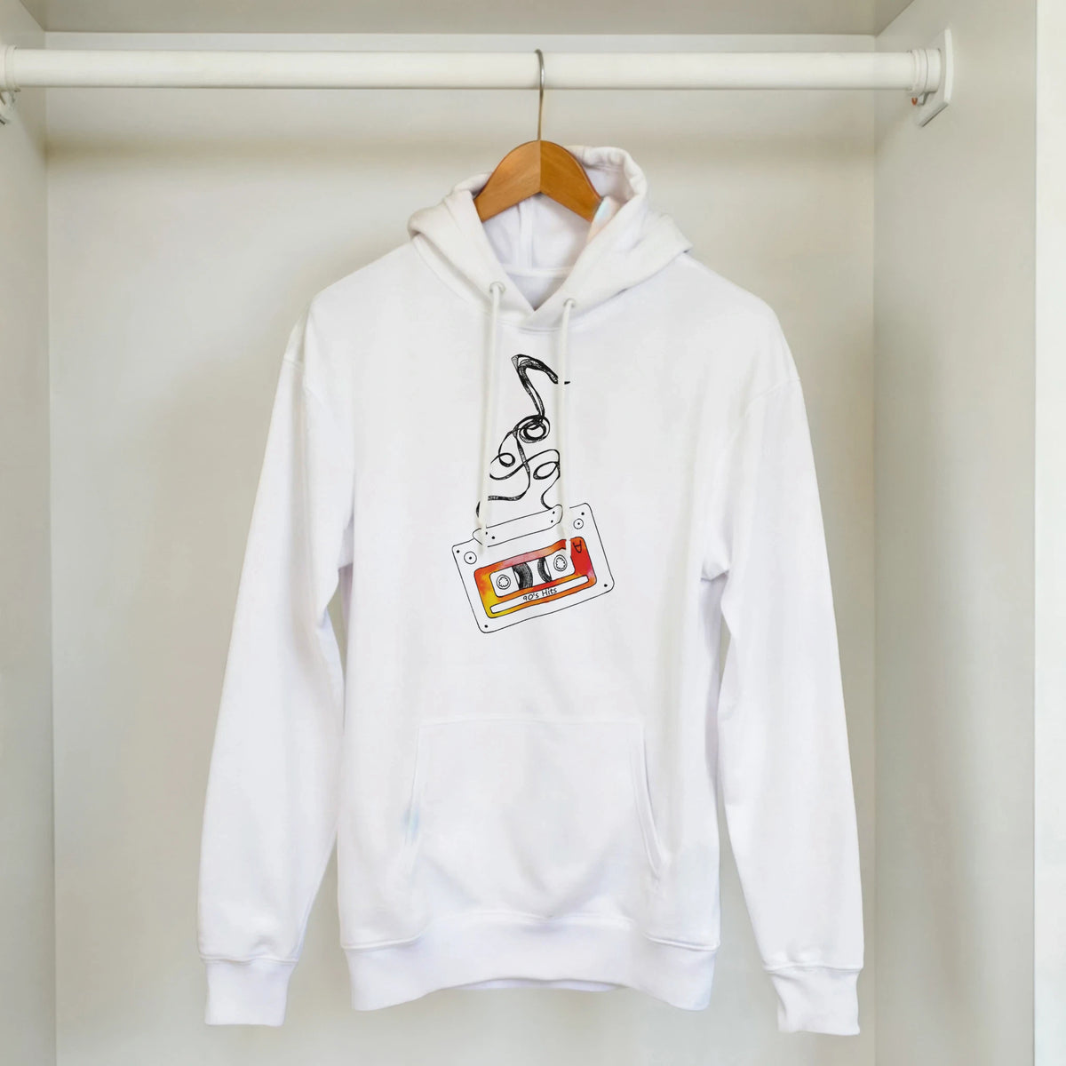 Retro cassette tape hoodie with vintage music graphic on white pullover, hanging on a wooden hanger in a closet