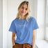 Woman in a blue T-shirt featuring a white RareFind logo, casual urban streetwear.