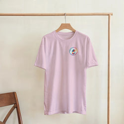 Pastel pink ladies tee with small colorful retro palm tree graphic on chest, hanging on wooden rack for casual style.