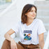 Woman wearing Tropical Paradise Graphic T‑Shirt in white, soft cotton blend with palm trees and sunset island design.