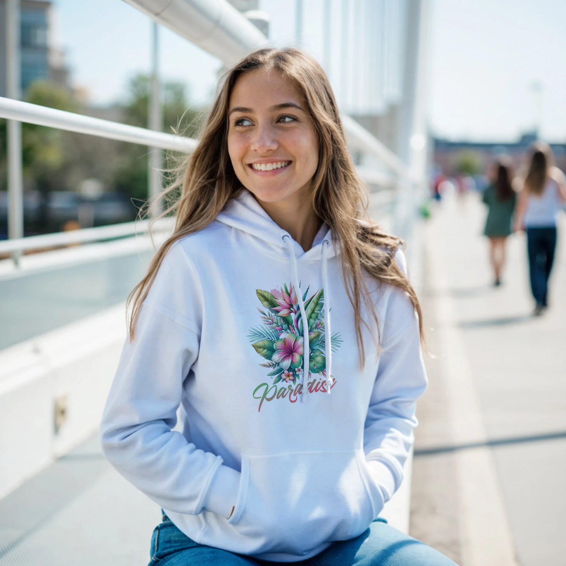 Woman wearing a white Y2K Paradise hoodie with tropical palm leaves on an urban walkway.