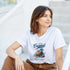 Woman wearing a white Coconut Beach graphic T-shirt with a tropical coconut illustration and blue text.