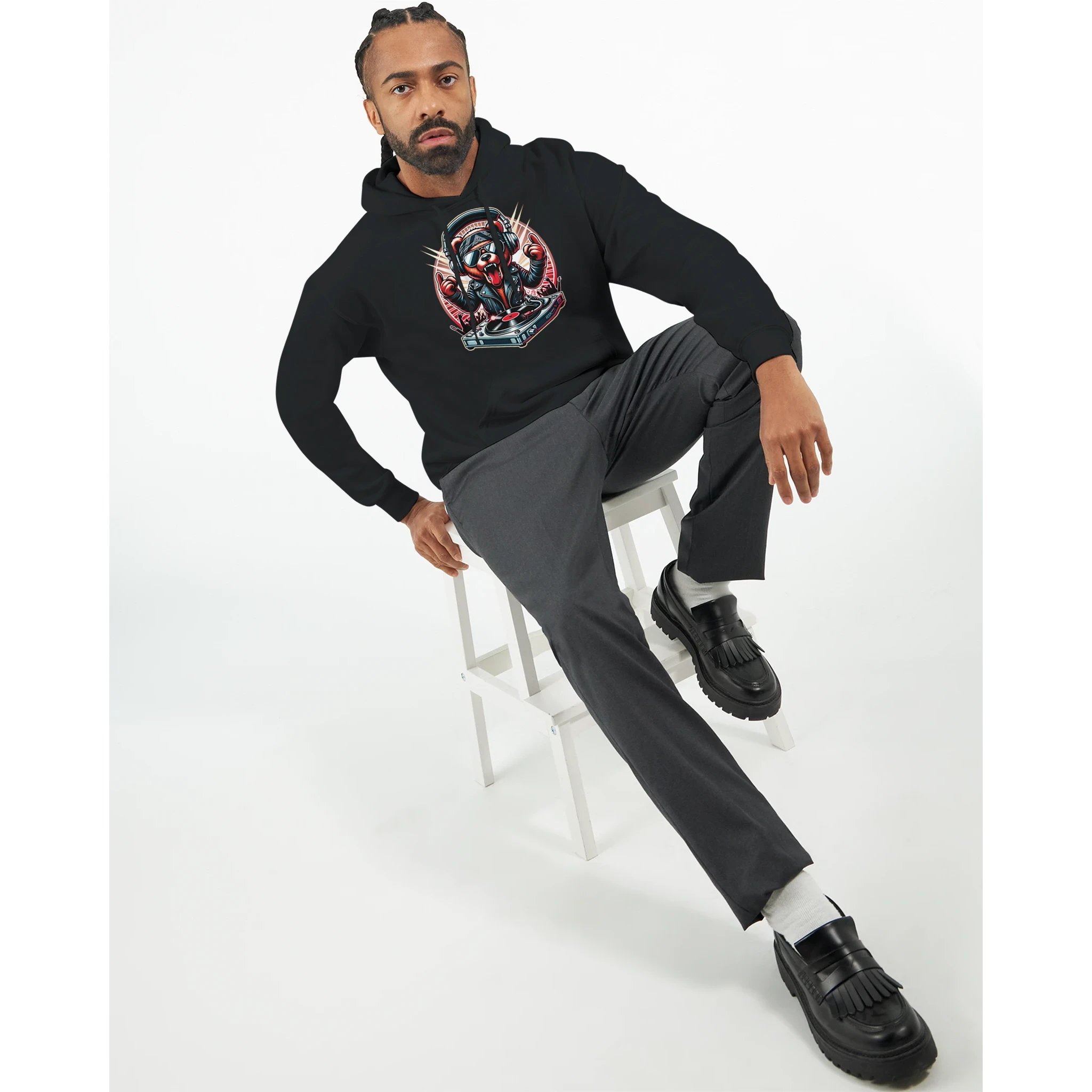 Man wearing black DJ Bear Hoodie with bold graphic, seated on a white stool.