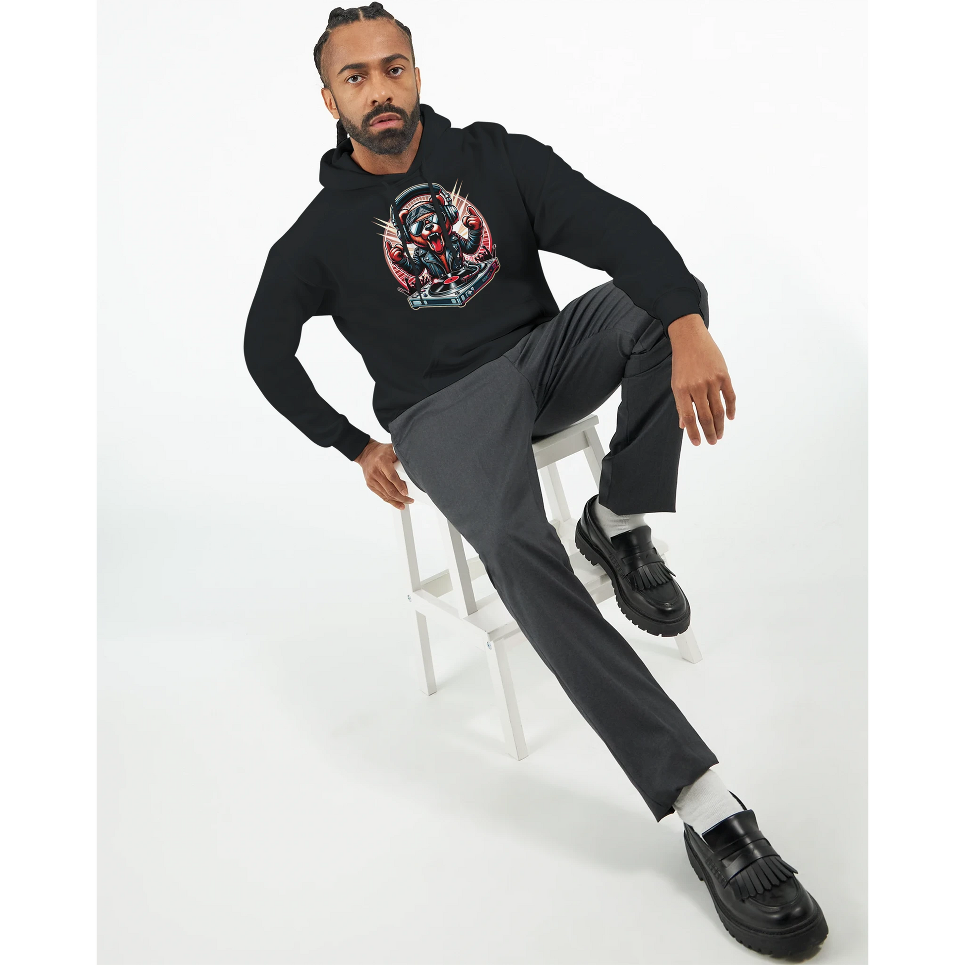 Man sitting on a stool wearing a black men's bear hoodie with a colorful graphic and gray pants.