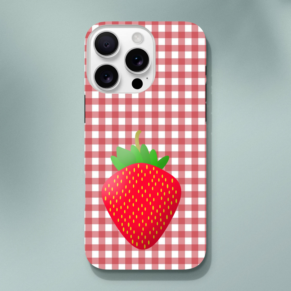 Red checkered gingham iPhone case featuring a large cute strawberry graphic, designed for drop protection on iPhone 13-16 models.