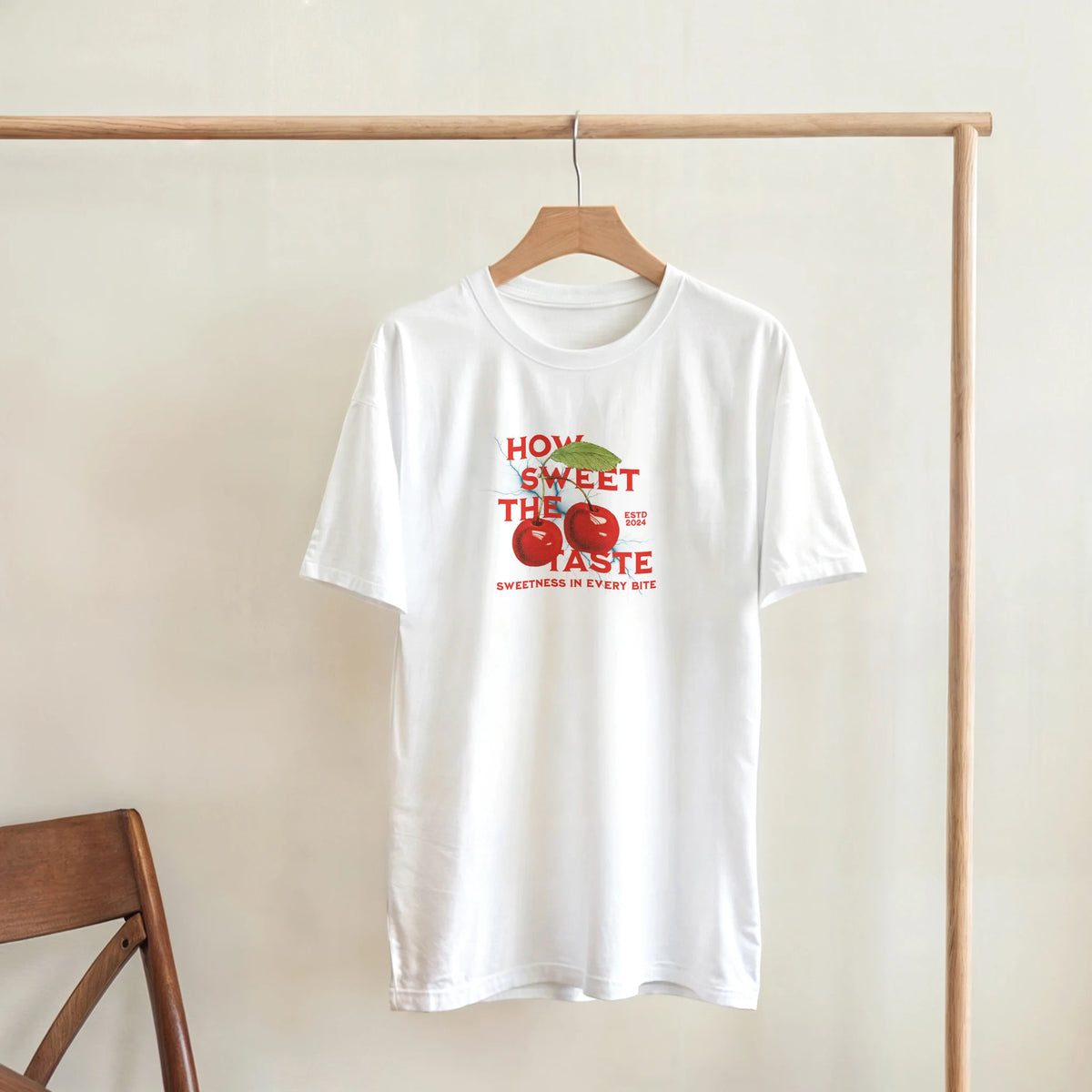 White tee with retro red cherry graphic and "HOW SWEET THE TASTE" text, a cute fruit graphic shirt for women.