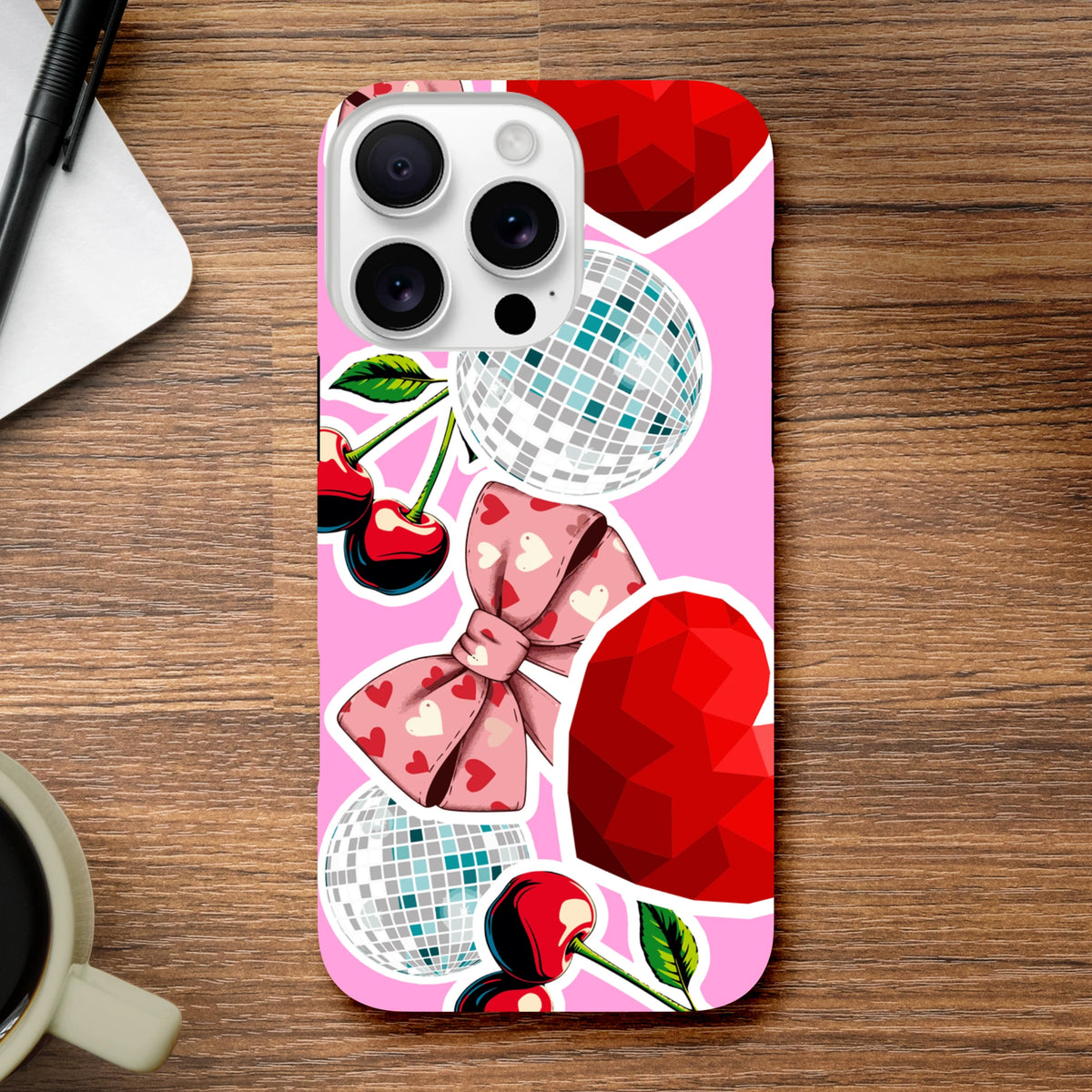Pink iPhone case featuring sticker-style cherries, disco balls, and a heart-patterned bow for Y2K aesthetic protection.