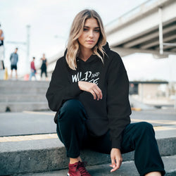 Woman wearing Cute Wild And Free hoodie with bold slogan in urban setting on steps.