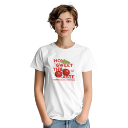 Woman modeling a white retro sweet cherry graphic t-shirt featuring bold red fruit print and "How Sweet The Taste" text.