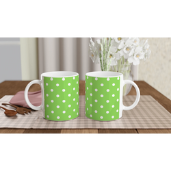 Two green ceramic mugs with white polka dots sit on a checkered placemat beside wooden spoons and white flowers.