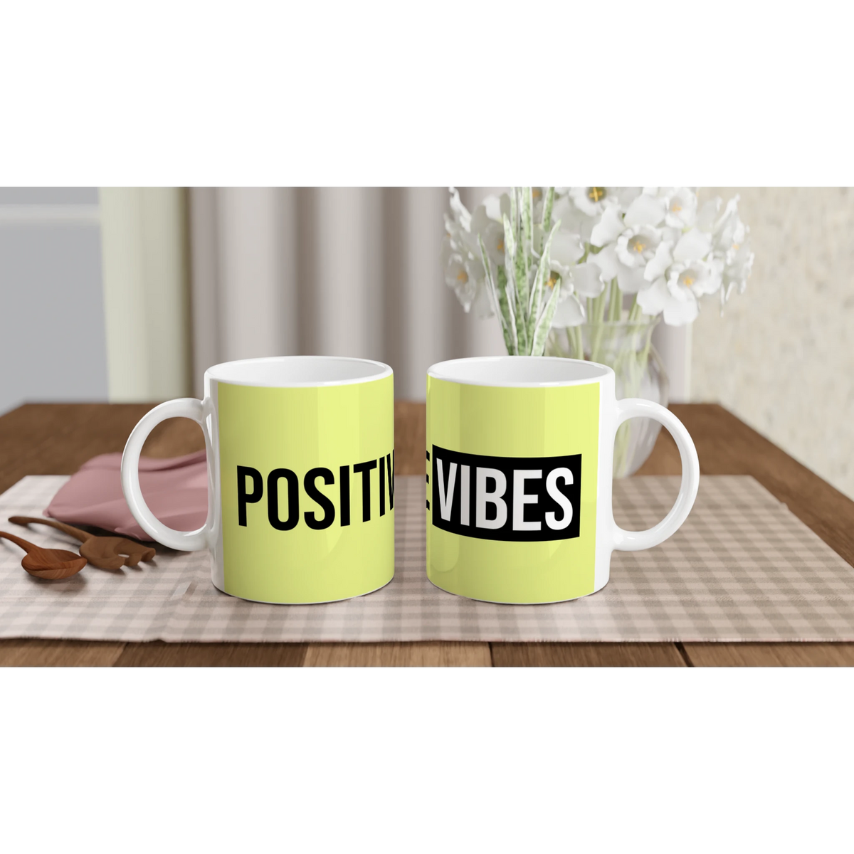 Two lime mugs with bold POSITIVE VIBES text on a wooden table; floral bouquet in the background.