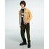 Male model wearing a black mental health graphic T-shirt under a tan jacket and olive pants.