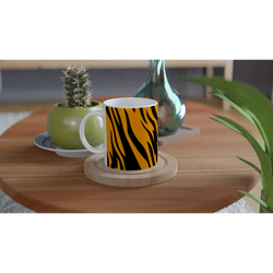 Orange and black tiger-print mug on a wooden table beside a small cactus and green vase.