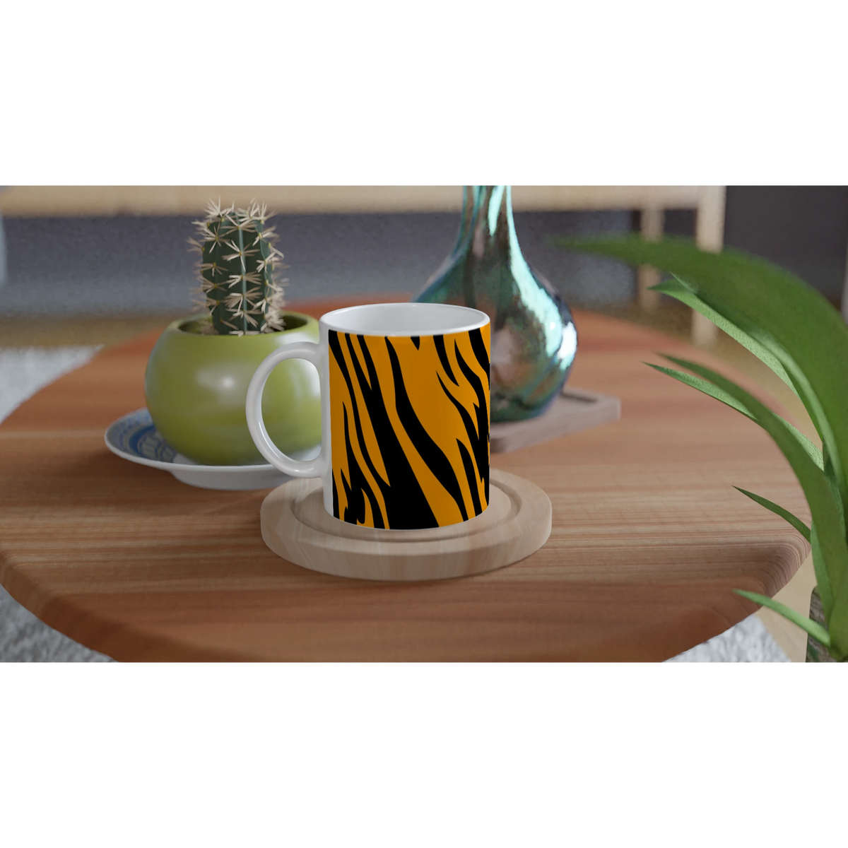 Orange and black tiger-print mug on a wooden table beside a small cactus and green vase.