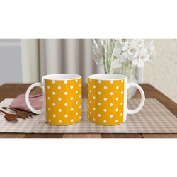 Pair of orange and white polka dot ceramic mugs sitting on a checkered placemat with wooden spoons and white flowers nearby.