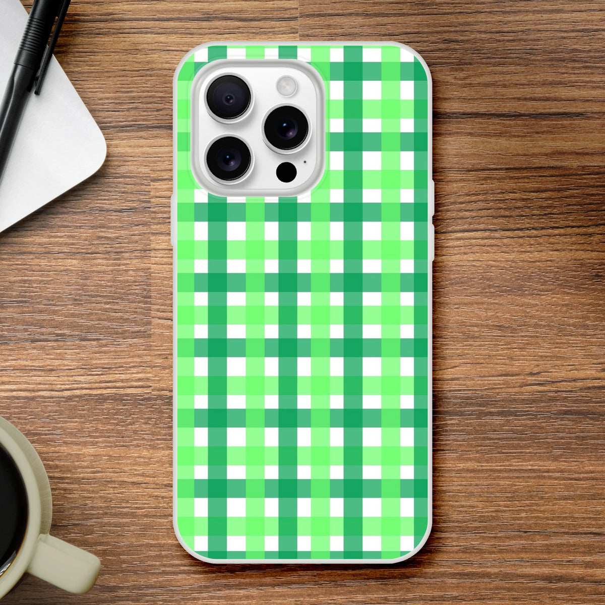 Green gingham iPhone case with bold checkered print on a wooden desk.