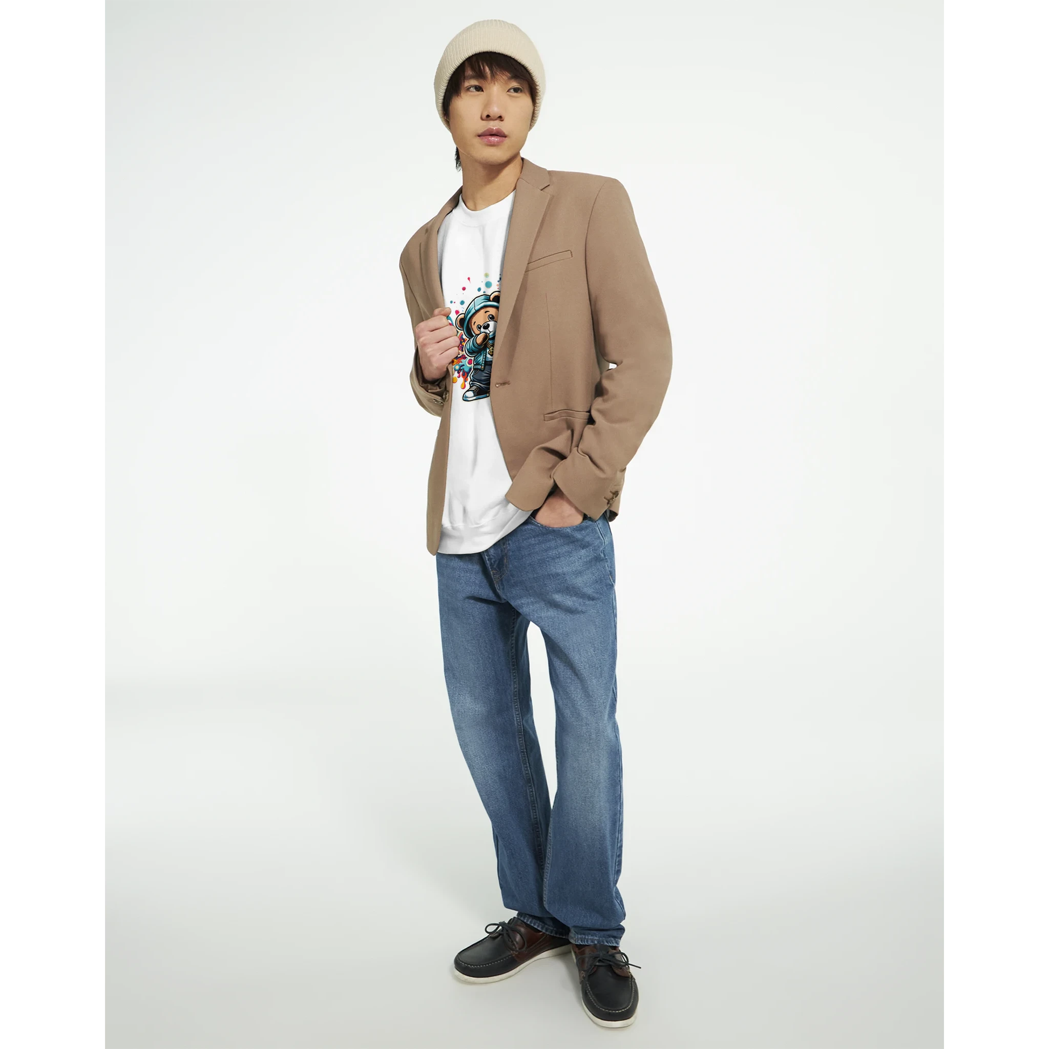 Male model in tan blazer wearing white Dab Teddy Bear graphic tee, blue jeans, beanie, casual streetwear.