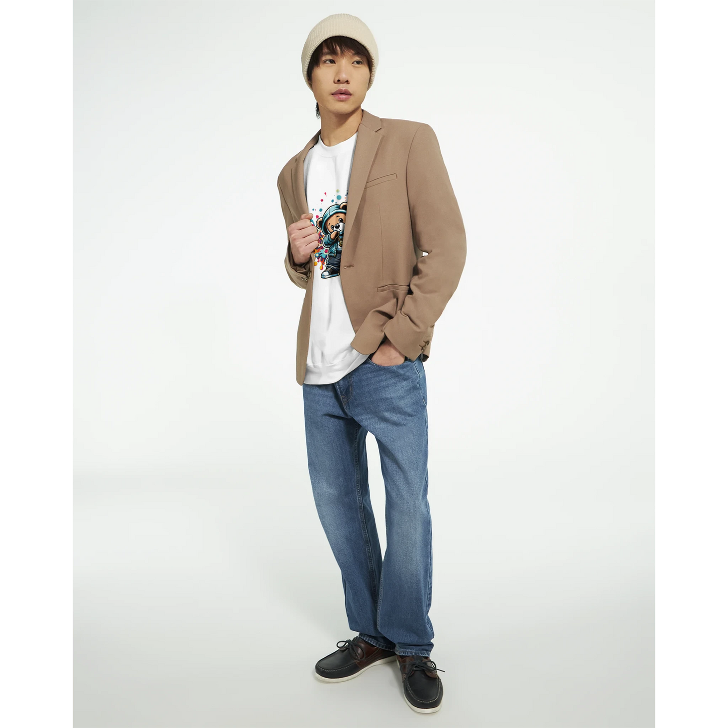 Person wearing a beige blazer, white men's graphic sweatshirt, blue jeans, and black shoes on a white background