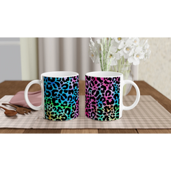 Retro leopard-print coffee mugs with rainbow gradient; two white handles on a checkered tablecloth.