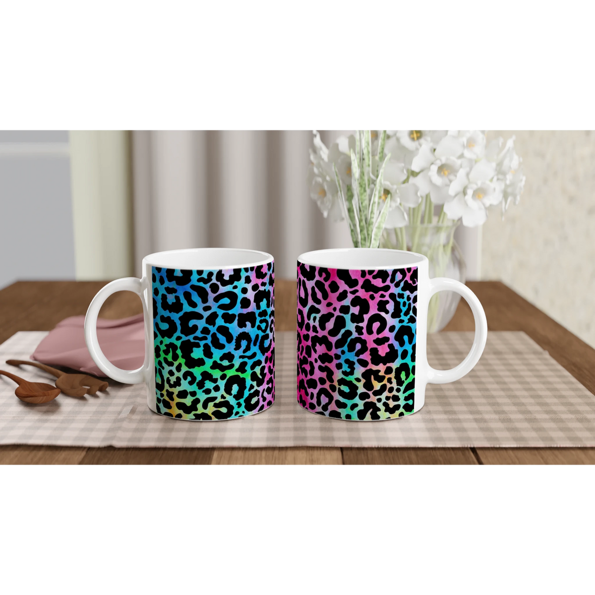 Retro leopard-print coffee mugs with rainbow gradient; two white handles on a checkered tablecloth.