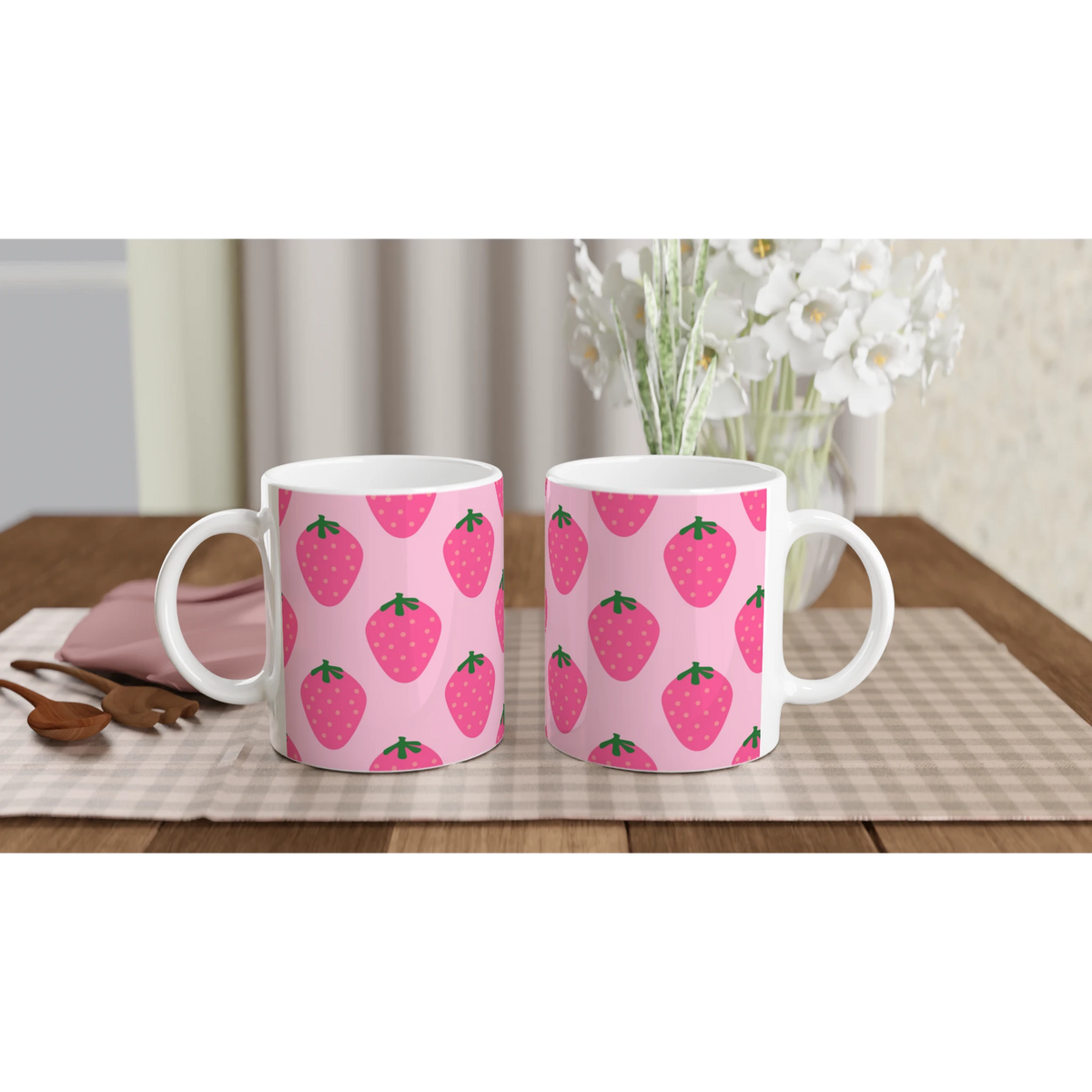 Pair of pink strawberry-pattern mugs on a checkered table, kawaii fruit coffee cups.
