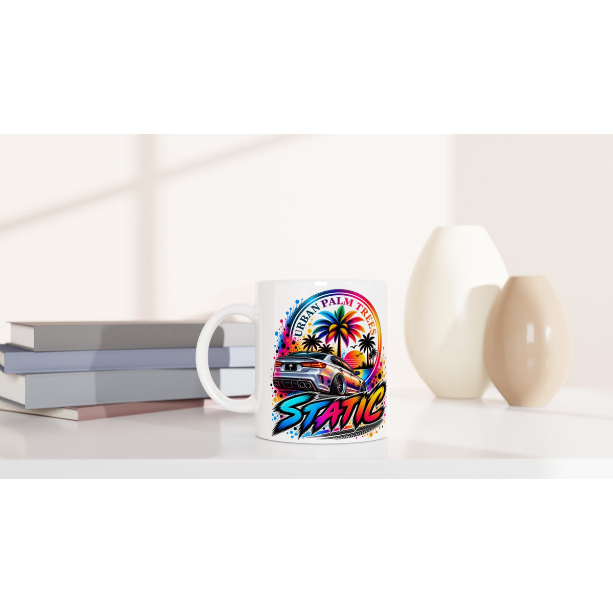 White petrolhead mug featuring colorful car and palm tree static design on a desk with books.