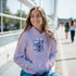 Woman wearing lavender soft cotton-blend hoodie with front pocket and 'It's OK Not To Be OK' graphic outdoors.
