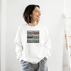 White vintage sweatshirt featuring a grid of six colorful retro cassette tape graphics for 90s music nostalgia.