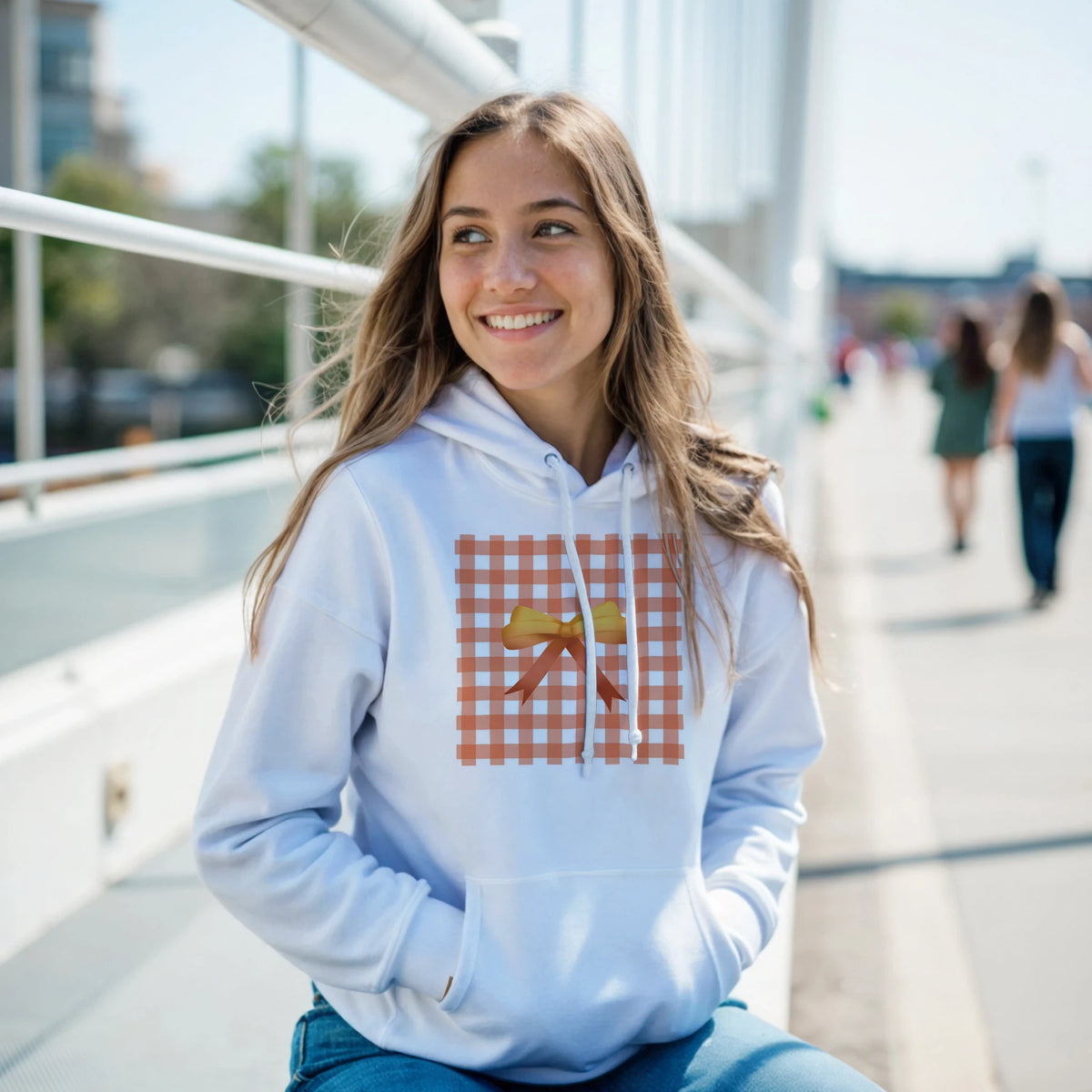 White pullover hoodie featuring an orange gingham square with a yellow bow, showcasing a cute coquette aesthetic streetwear design.