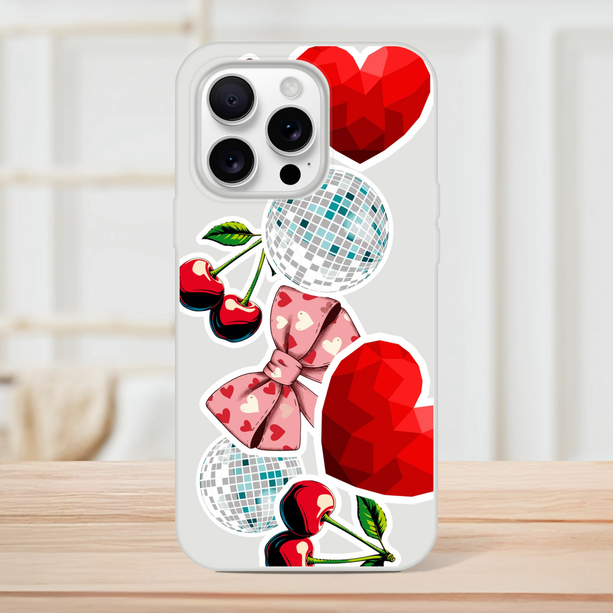 Transparent iPhone case featuring Y2K sticker art with glossy cherries, disco balls, and a pink bow on a clear glossy shell.