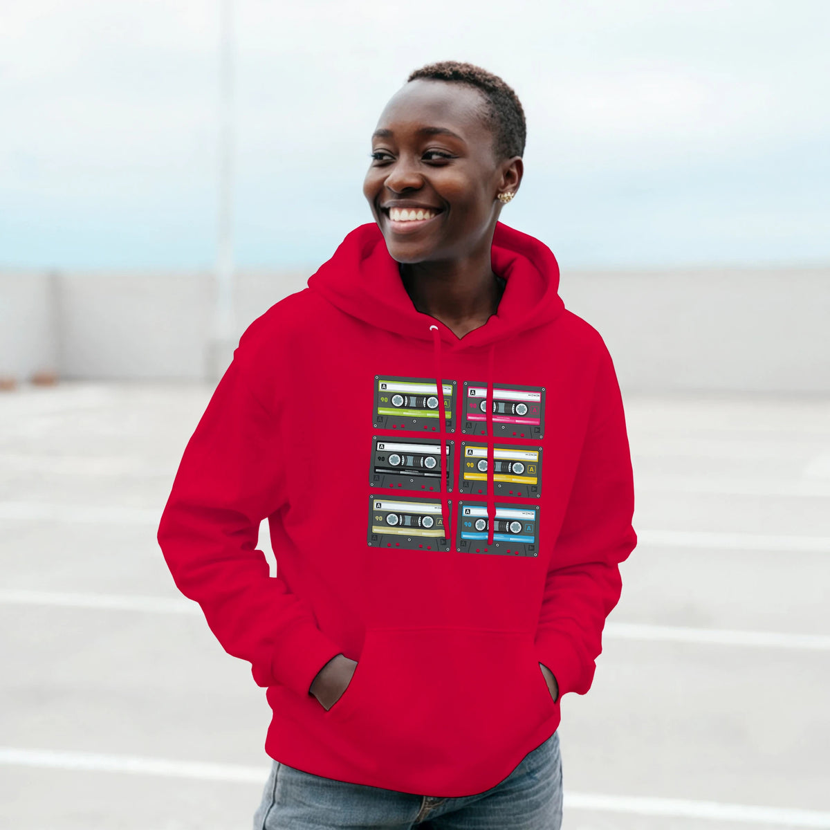 Smiling person in a red Retro Cassette Tape Hoodie for Men with stacked cassette graphics.