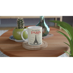 Vintage Paris mug with Eiffel Tower illustration on a wooden table beside a small cactus and a green vase.