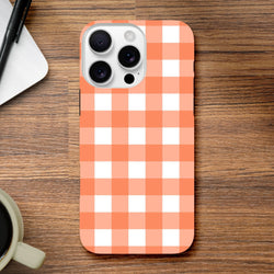 Orange and white gingham iPhone case with retro checkered pattern on wooden desk, featuring tough shock-absorbing design for daily use.