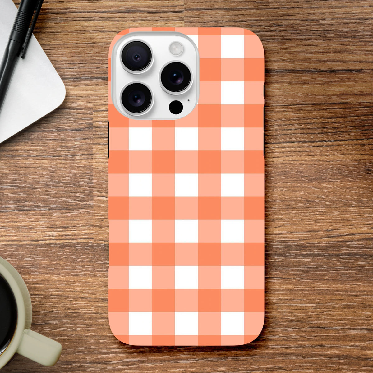 Orange and white gingham iPhone case with retro checkered pattern on wooden desk, featuring tough shock-absorbing design for daily use.
