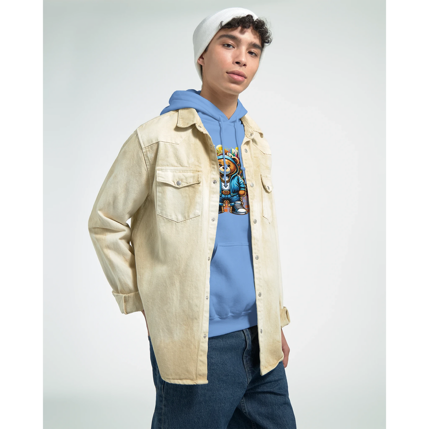 Person wearing a beige jacket, blue men's teddy bear hoodie, and jeans on a light gray background
