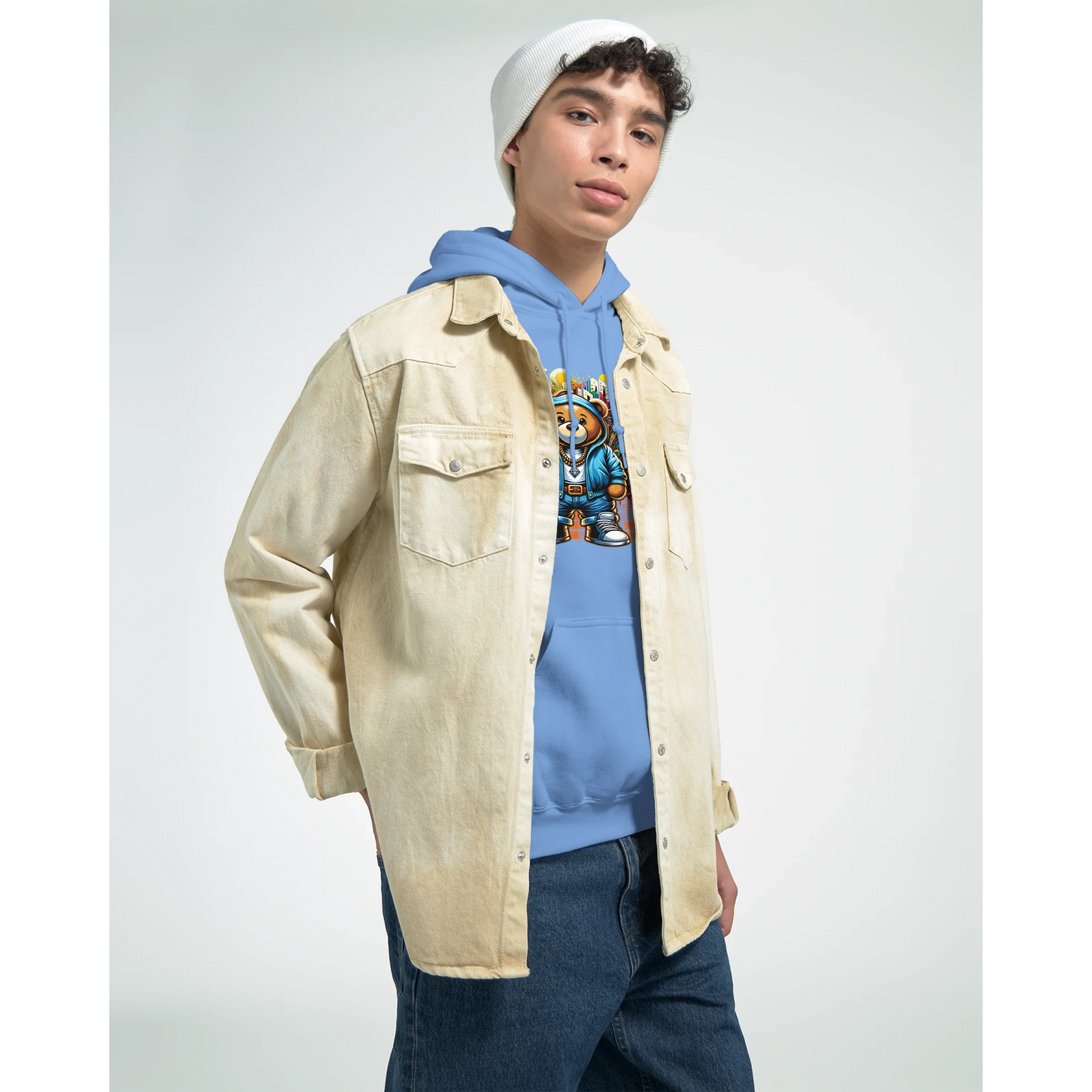 Person wearing a beige jacket, blue men's teddy bear hoodie, and jeans on a light gray background