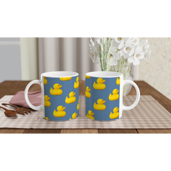 Two ceramic mugs with yellow rubber ducks printed on a blue background on a table.