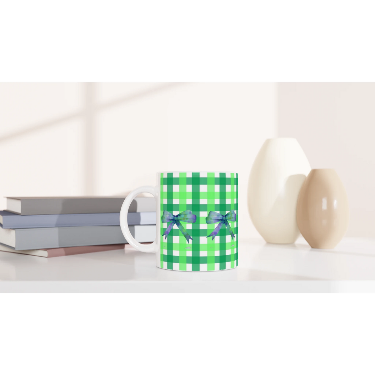 Green gingham bow mug with purple ribbons on a desk beside books.