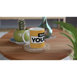 Yellow Believe In Yourself mug with bold slogan on a wooden table beside a cactus and plants.