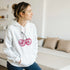 Glitter Ball Cherries jumper hoodie: white cotton blend with pink glitter cherry graphic worn by a woman.